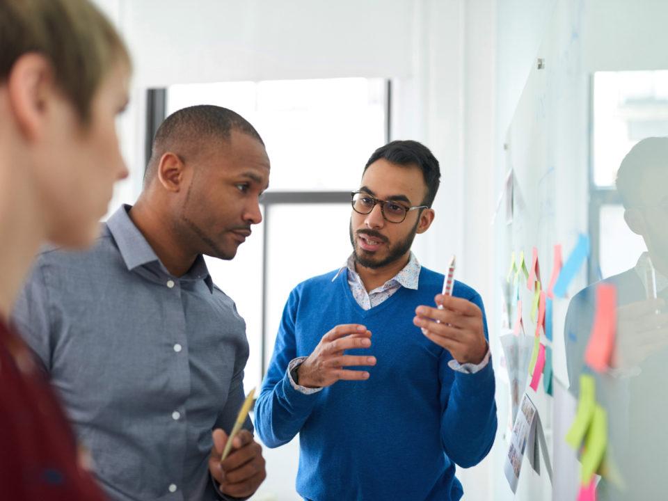 Portrait of an indian man in a diverse team of creative millennial coworkers in a startup brainstorming strategies